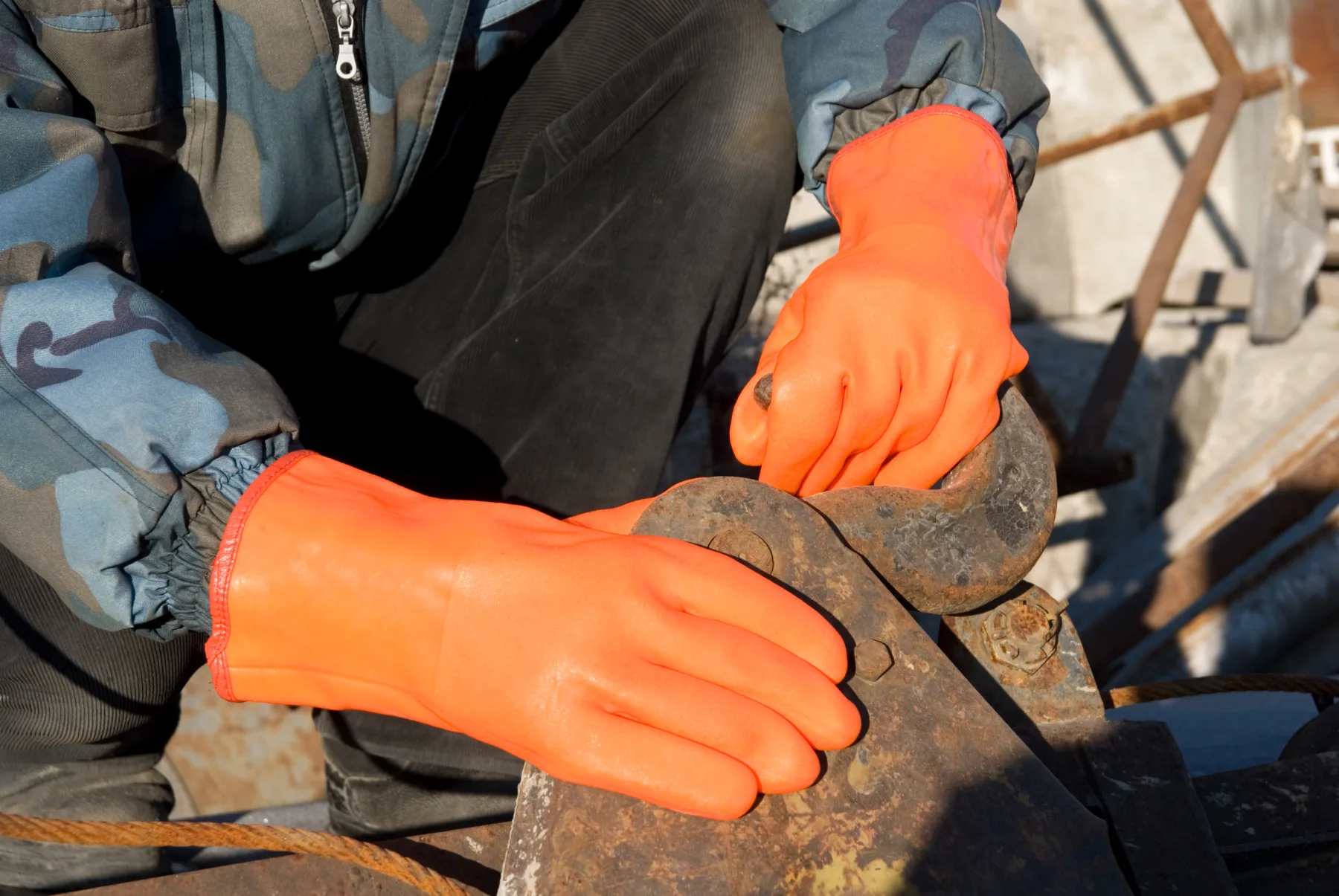 Trabajador manipulando un equipo con guantes protectores naranjas
