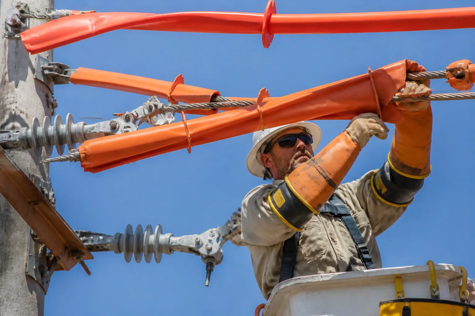 Técnico instalando mangueras y cubridores aislantes sobre líneas eléctricas